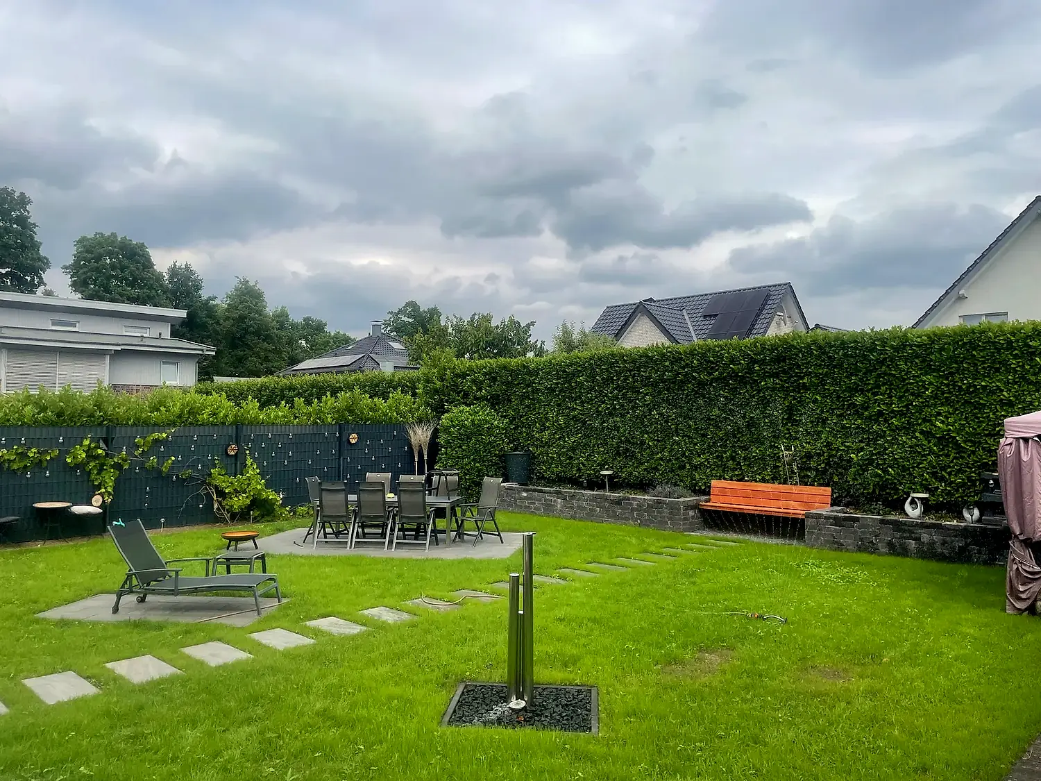 Fertige Terrassenanlage mit Sitzbereich, Rasen und Natursteinmauer, angelegt von Fortkamp