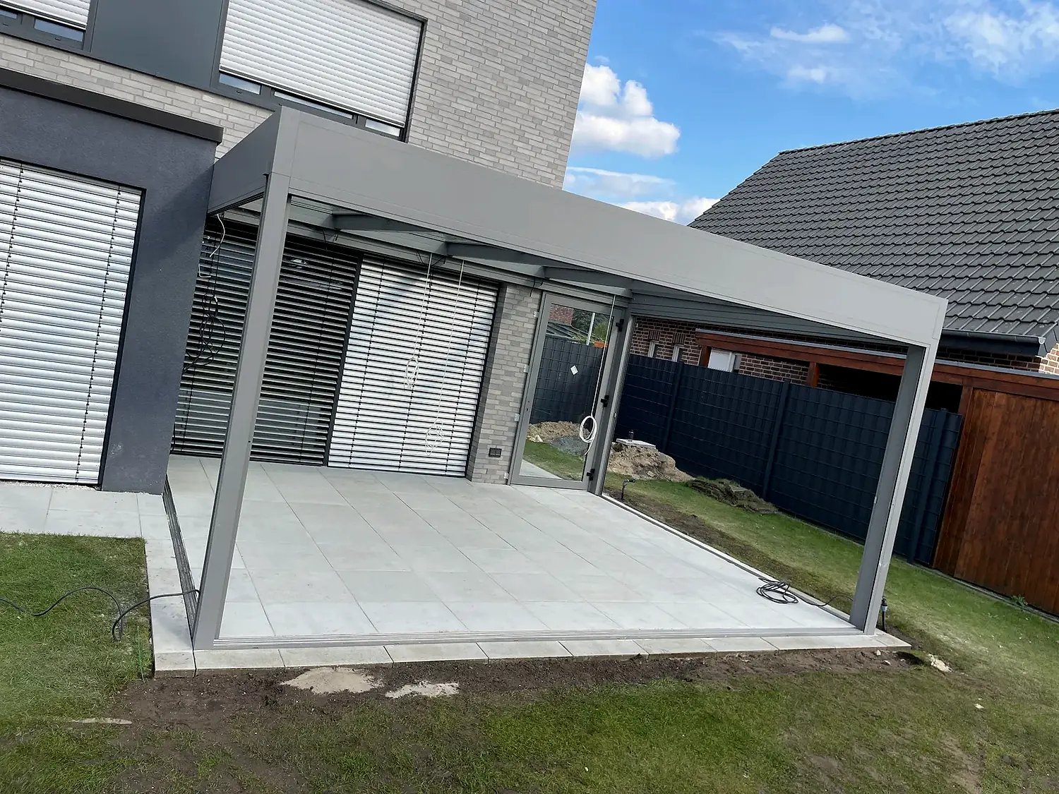 Moderne Terrassenfläche mit großformatigen Platten unter einer Terrassenüberdachung